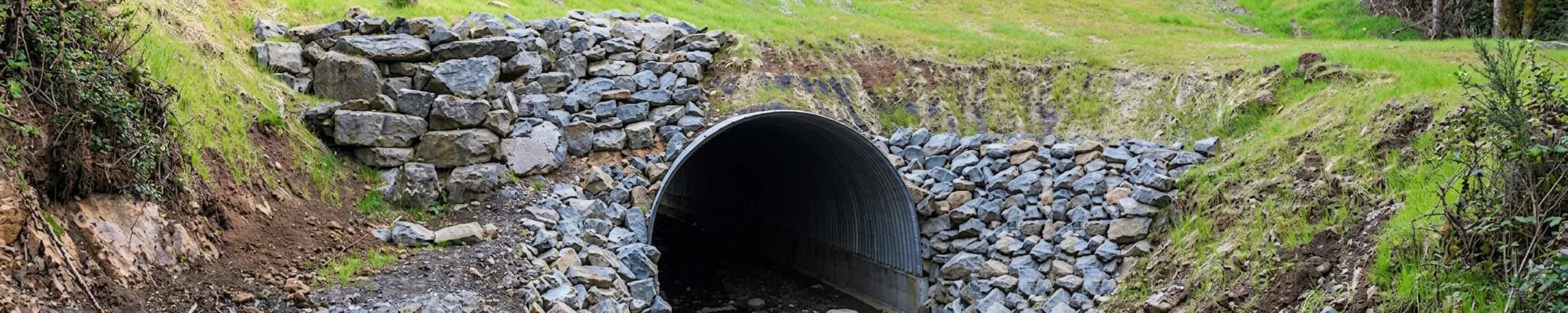Stone-lined railway culvert entrance beneath an embankment