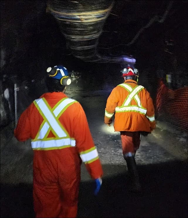 Mining safety team conducting tunnel inspection with advanced monitoring equipment